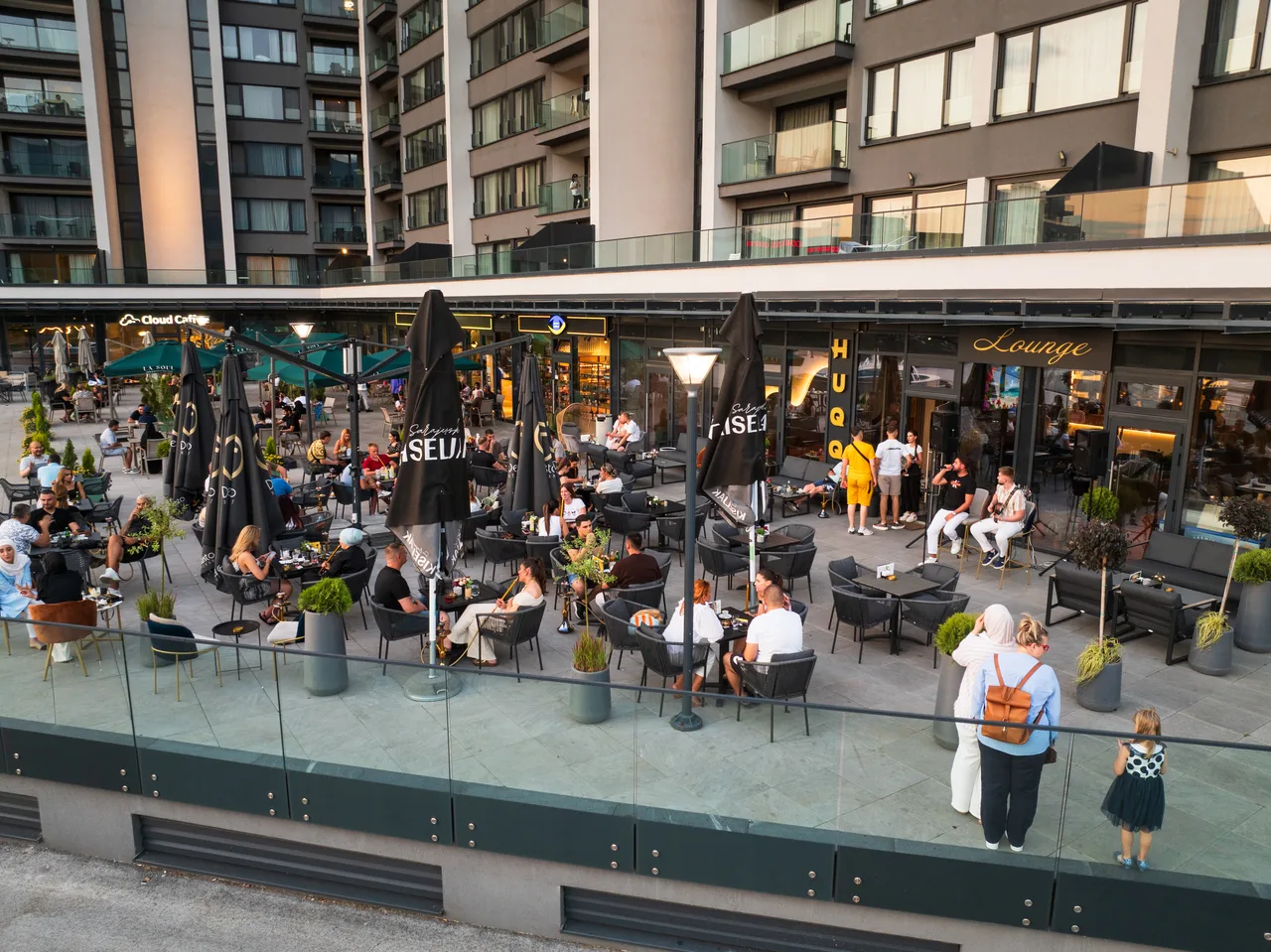 Guests at the café tables on the River Walk terrace in the evening