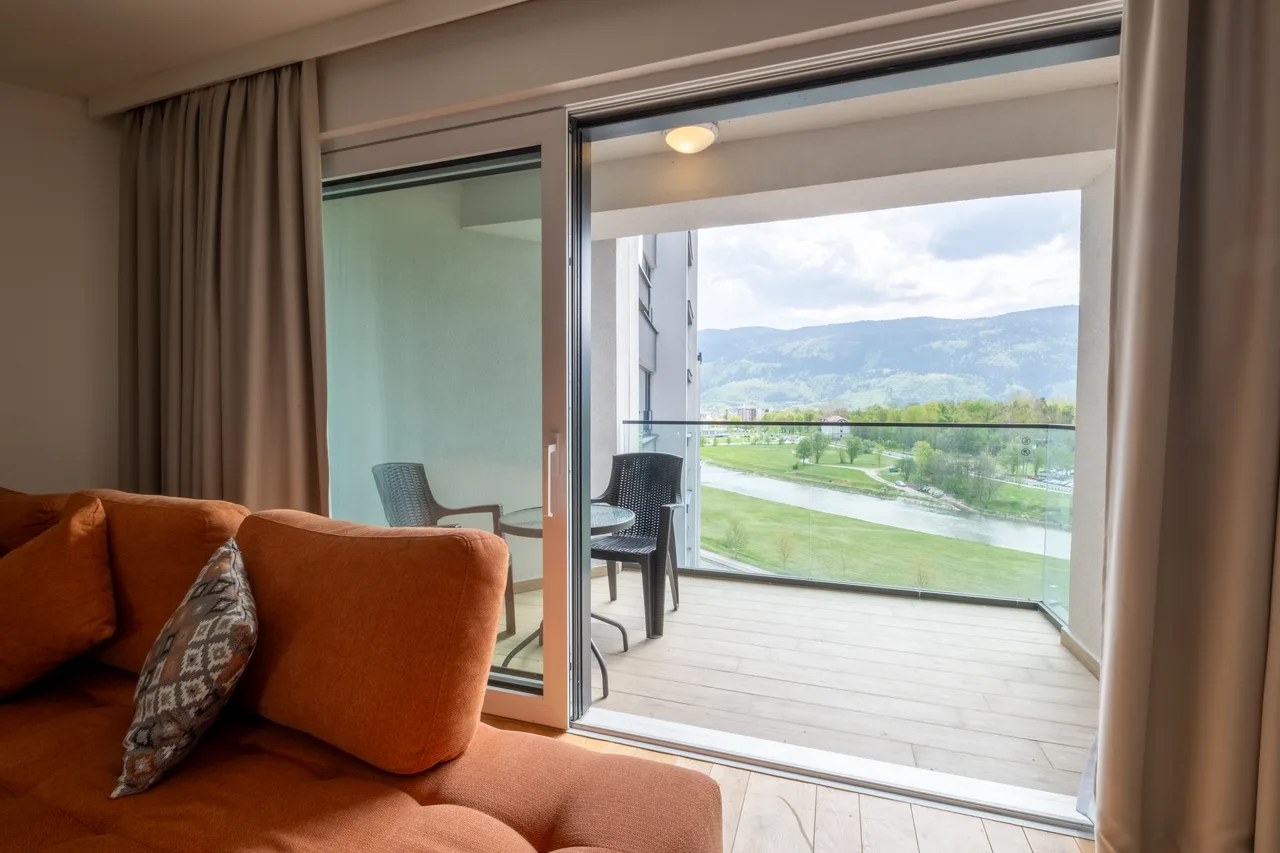 Outdoor space — One-bedroom apartment. Orange sofa and cream kitchen