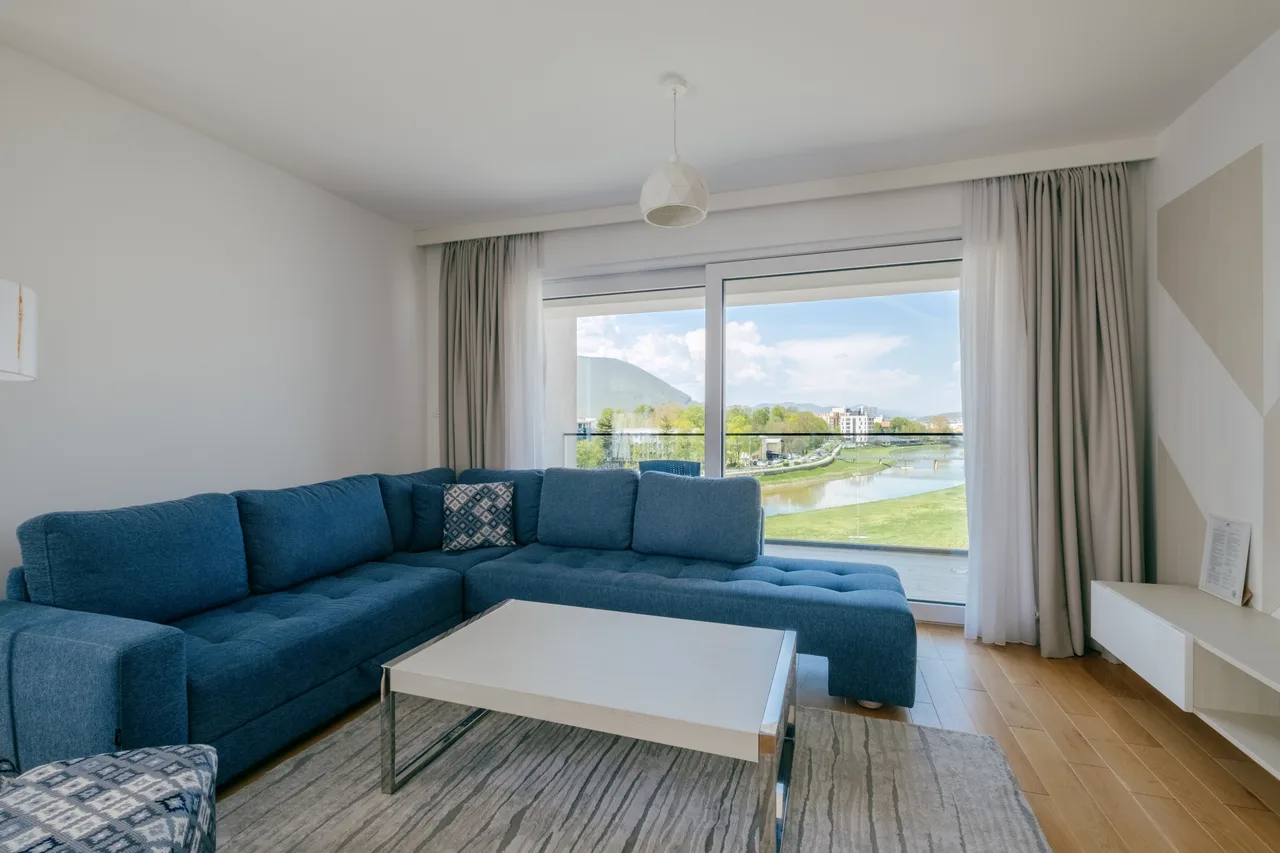 Living room — Two-bedroom apartment. Blue corner sofa and grey kitchen