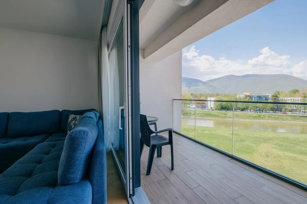 Outdoor space — Two-bedroom apartment. Blue corner sofa and grey kitchen